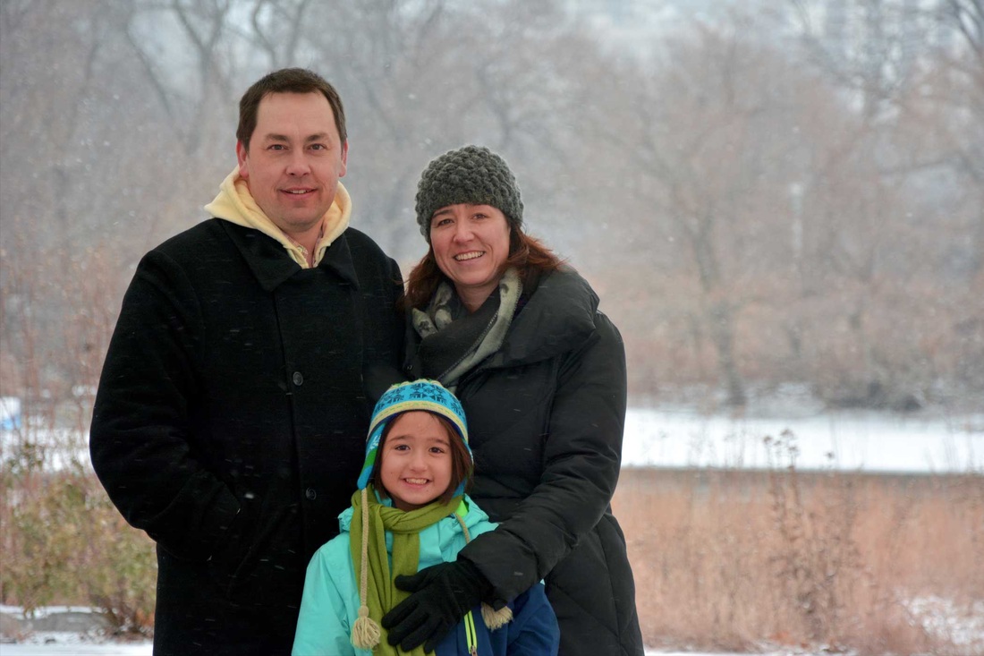 Two adults and a child gathered outdoors in the snow